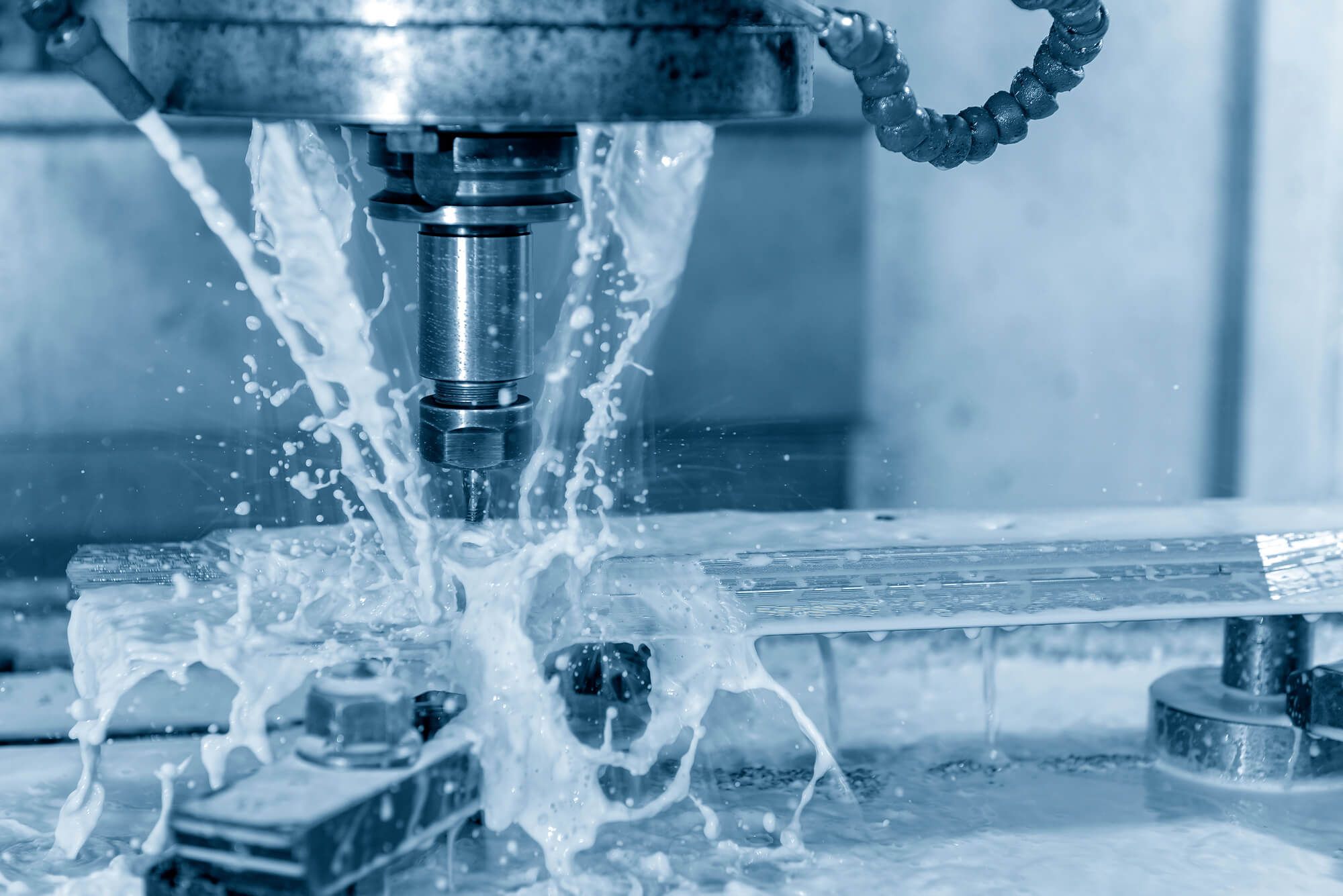CNC-Maschine in Betrieb mit Kühlmittelspritzern auf dem Metallteil.