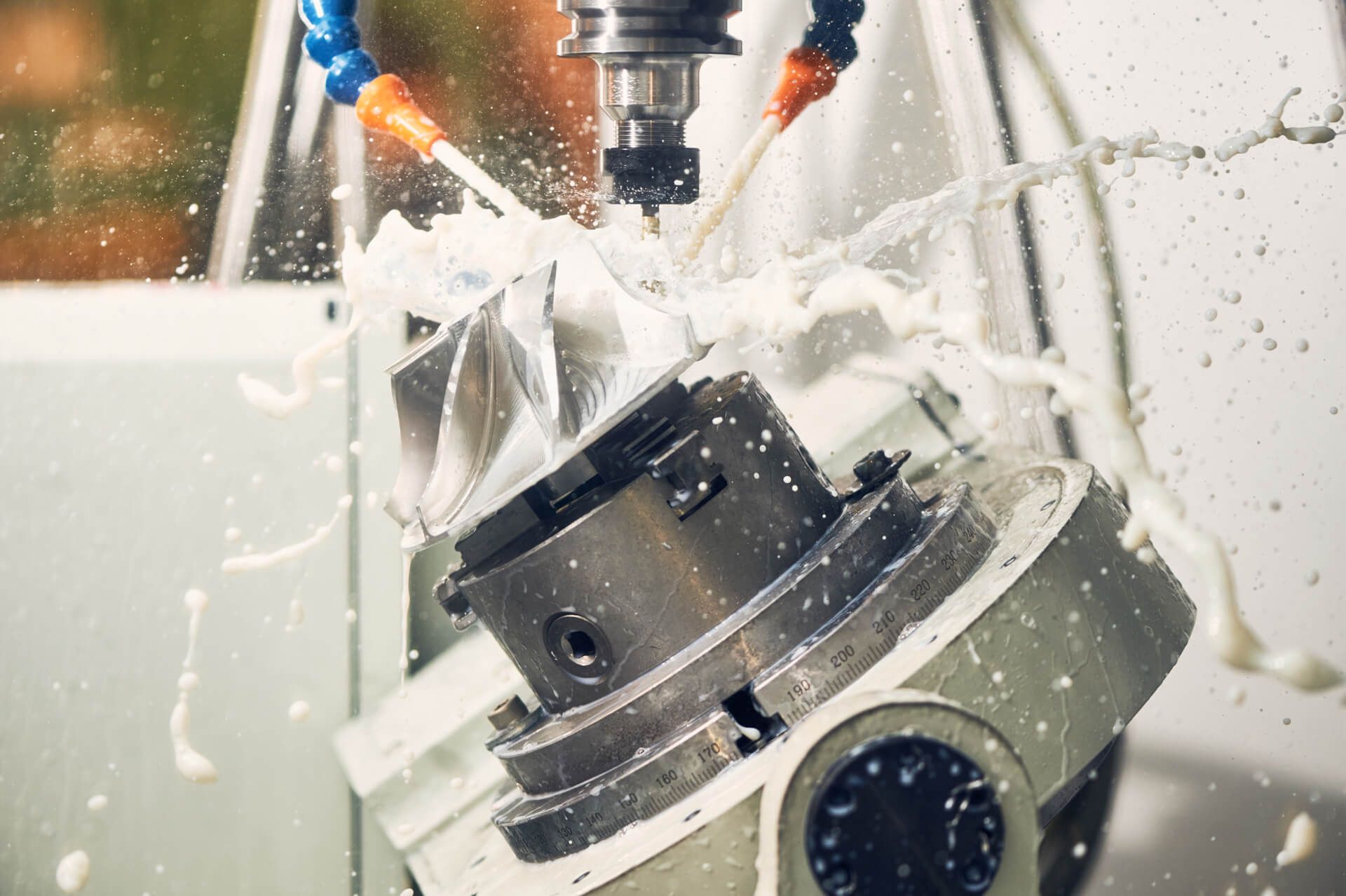 CNC-Maschine in Aktion mit Kühlmittelsprühung auf ein Metallteil.